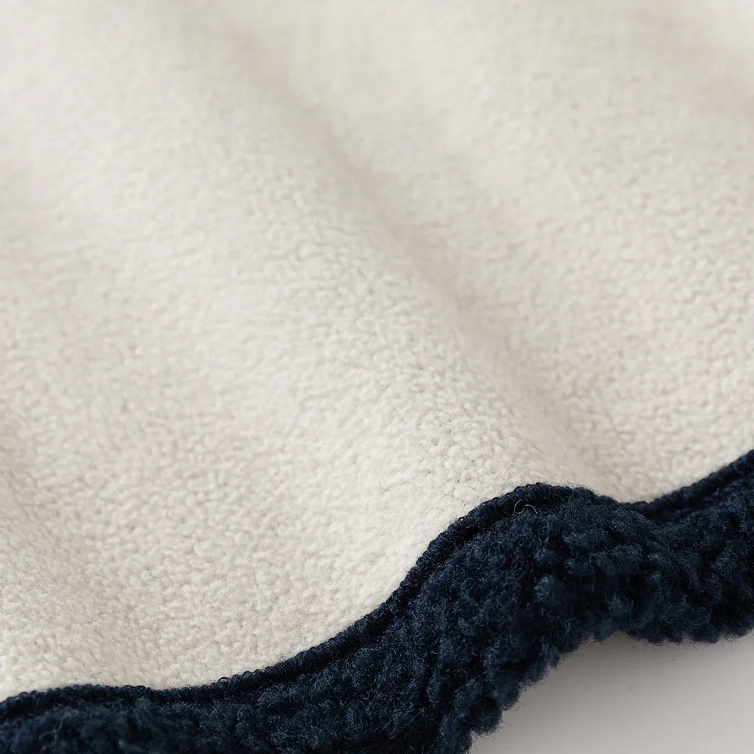Close-up of textured beige fabric with dark navy blue fleece trim