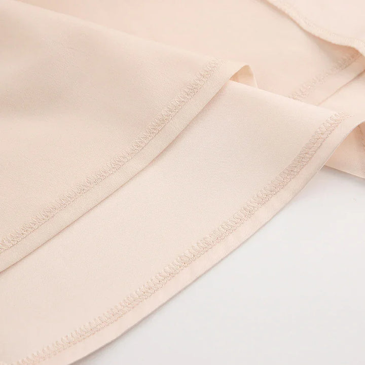 Close-up of beige lightweight fabric with visible stitching and smooth texture