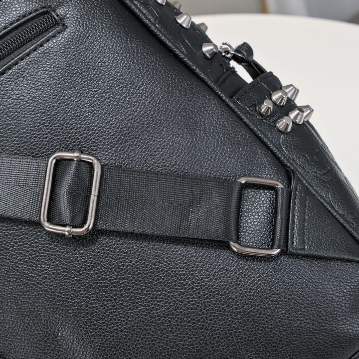 Black leather bag with adjustable black strap and metal buckles, featuring silver spikes on top