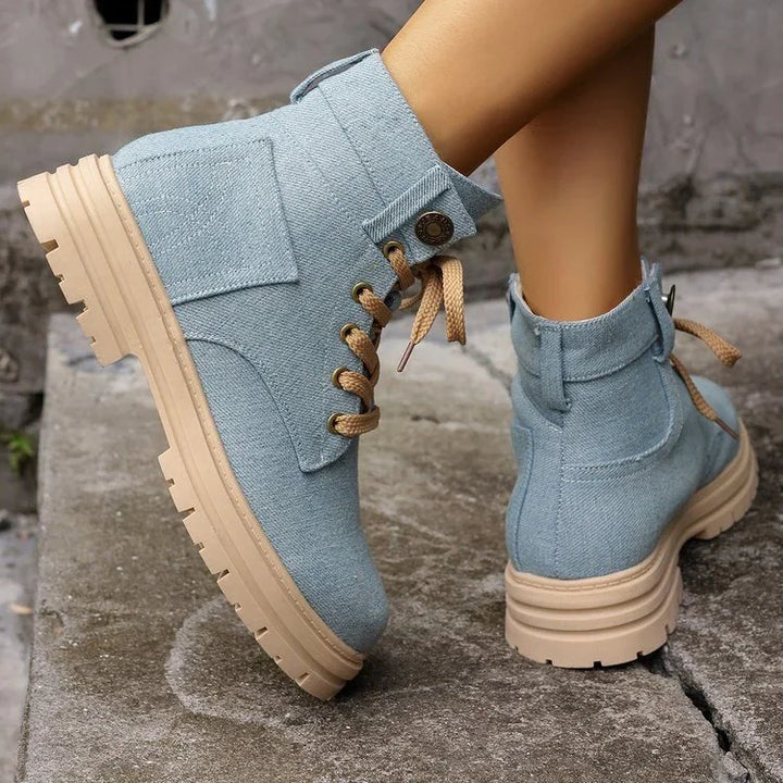 Light blue casual ankle boots with beige thick soles and tan laces worn on concrete steps