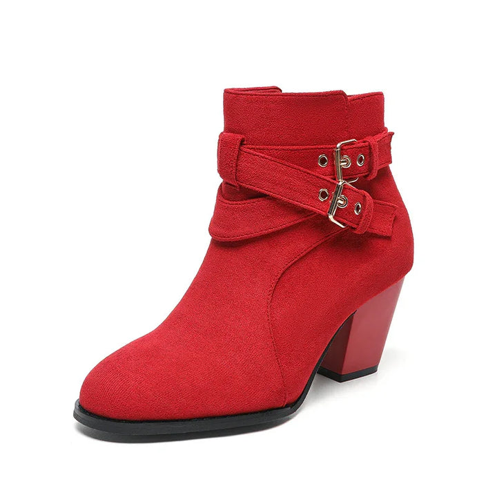 Red suede ankle boot with block heel and double buckle straps on white background