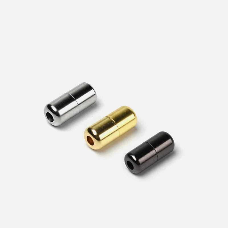 Three cylindrical metal magnetic clasps in silver, gold, and black on a white background