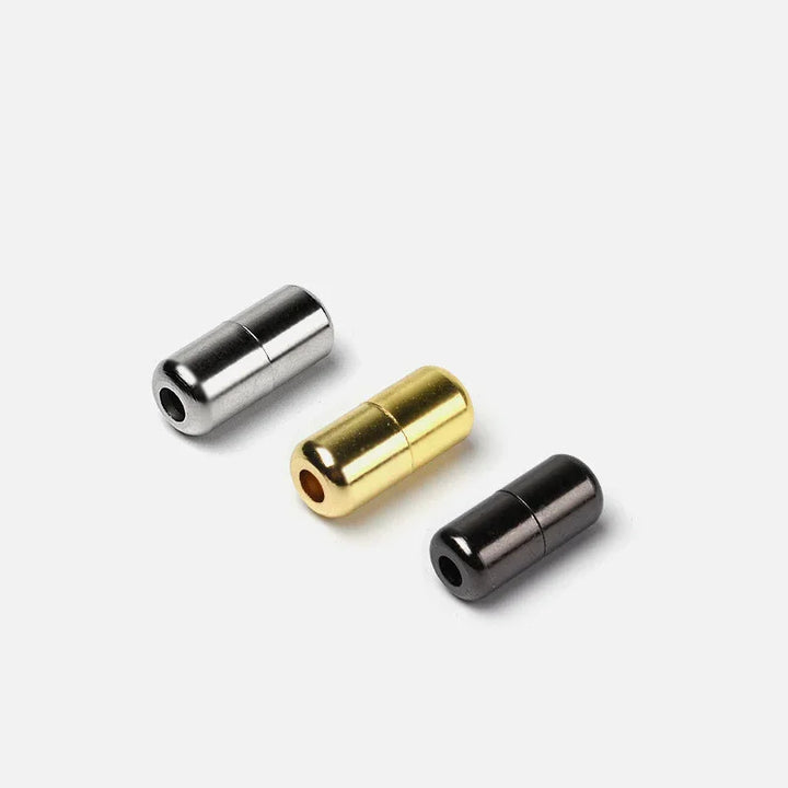 Three cylindrical metal magnetic clasps in silver, gold, and black on a white background