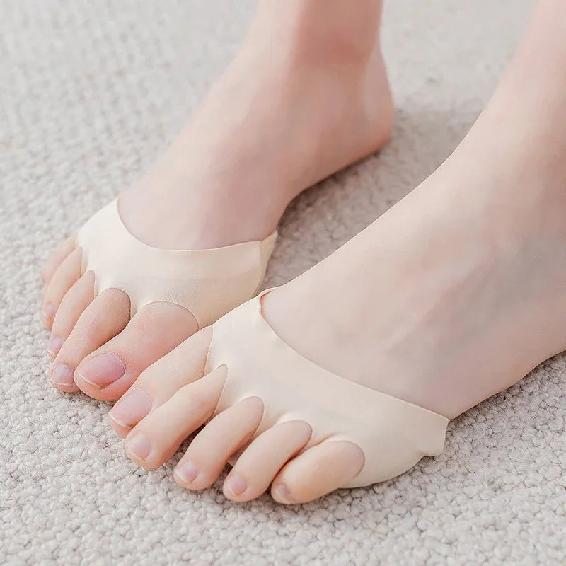 Bare feet wearing beige toe separator sleeves on light carpet for foot alignment support