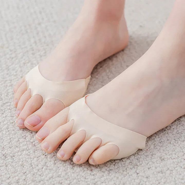 Bare feet wearing beige toe separator sleeves on light carpet for foot alignment support