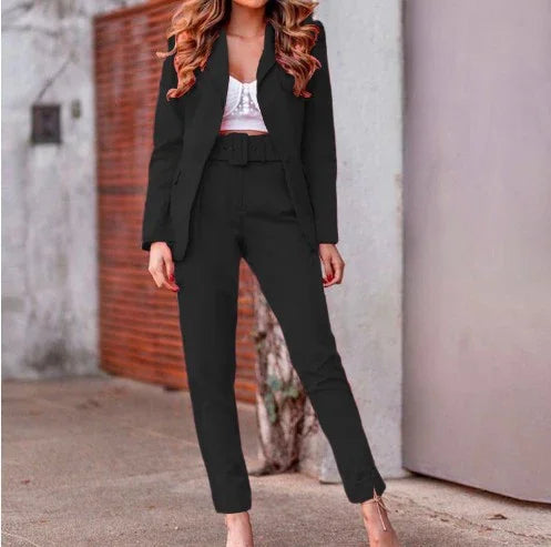 Woman wearing a black tailored pantsuit with a belted waist and white crop top, standing outdoors