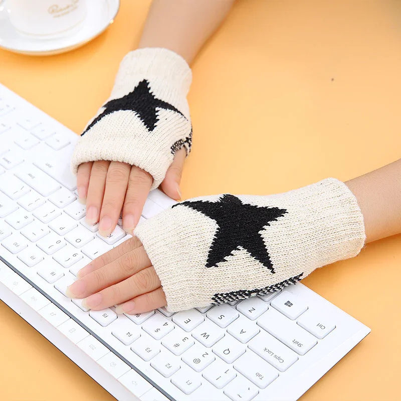 Hands wearing beige fingerless gloves with black star pattern typing on white keyboard