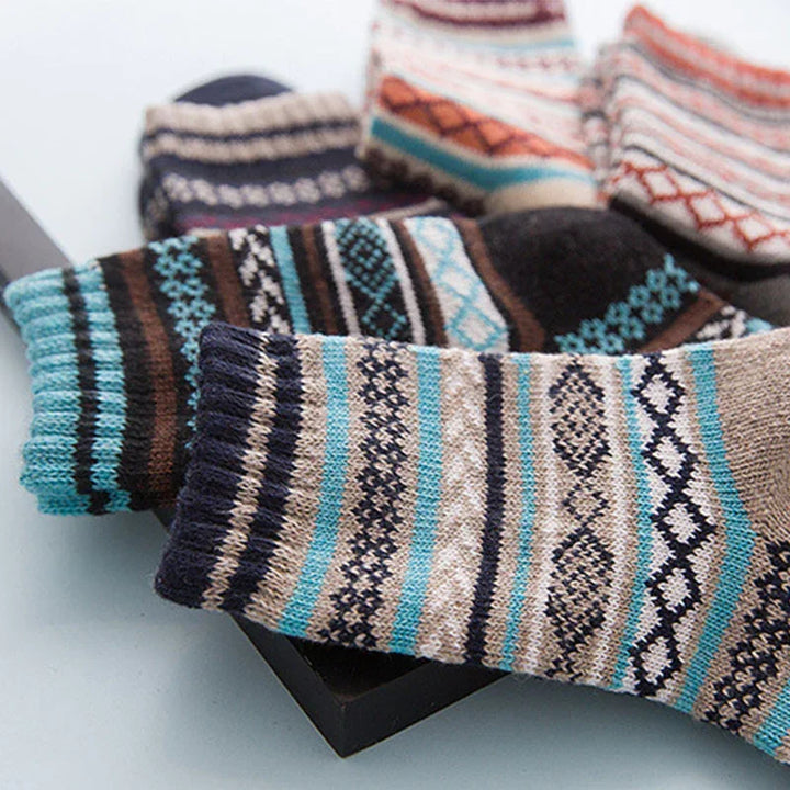 Colorful patterned wool socks with blue, beige, brown, and black geometric designs displayed in a black tray