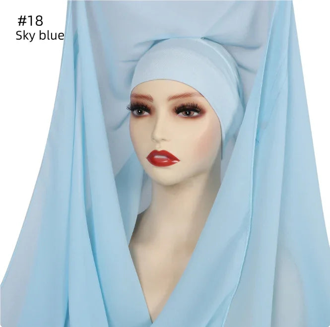 Mannequin head wrapped in sky blue fabric with dramatic makeup and long eyelashes