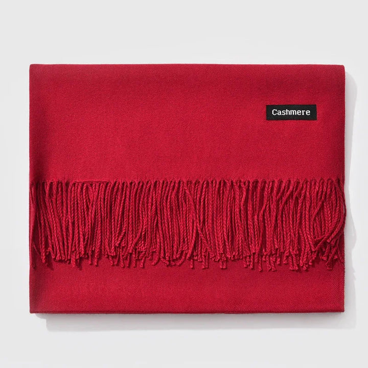 Folded red cashmere scarf with fringe detailing and Cashmere label on white background