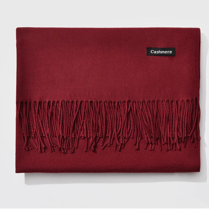 Folded burgundy cashmere scarf with fringe and black label on white background