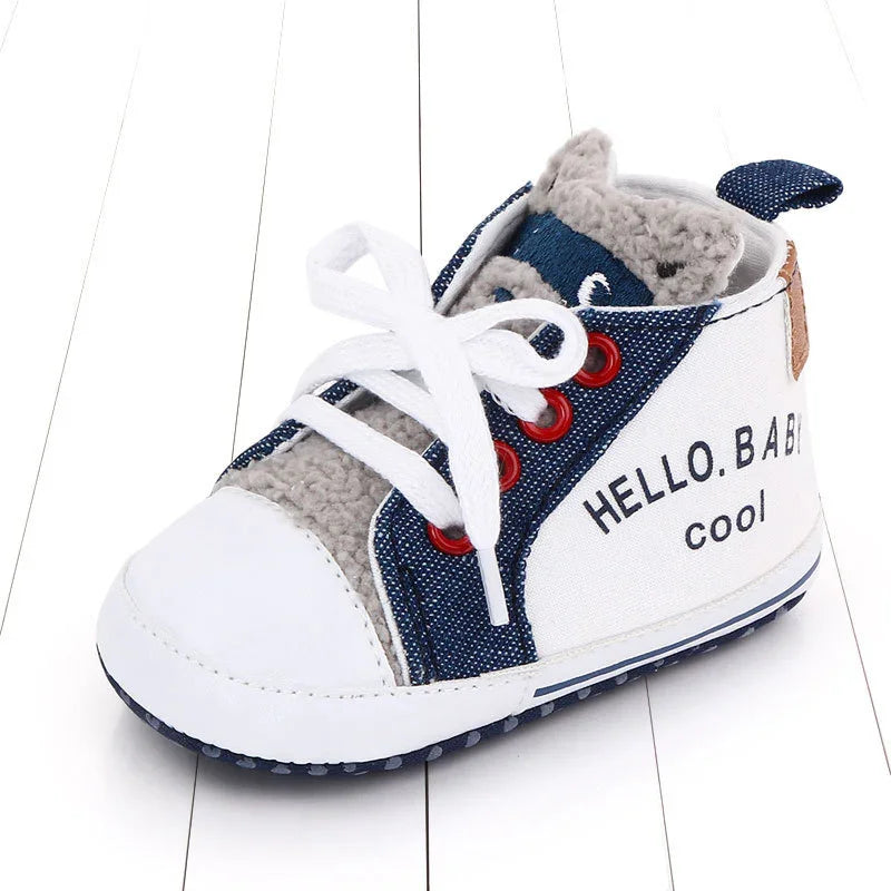 Baby sneaker with white toe, denim accents, fleece lining, red eyelets, and 'HELLO.BABY cool' text
