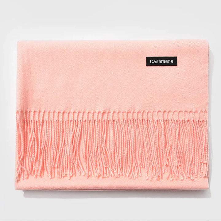 Soft pink cashmere scarf with fringed edges and black label on white background