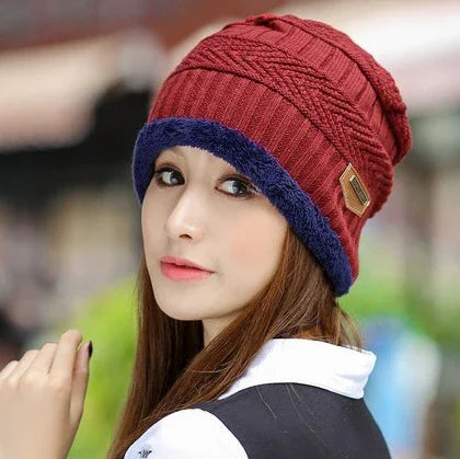 Young woman wearing a red and navy blue knitted winter beanie with a leather patch, outdoors