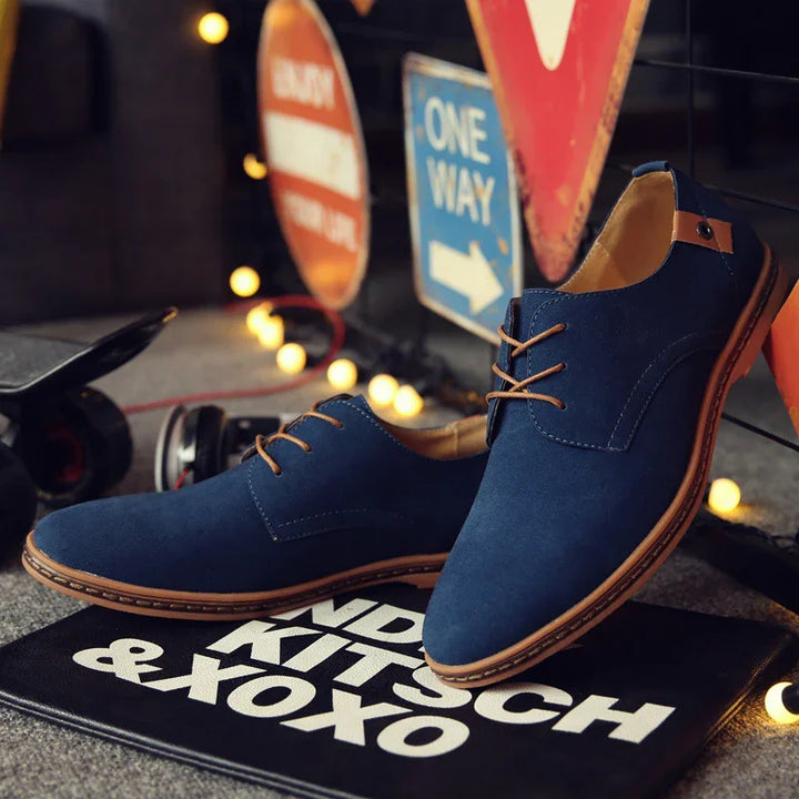 Navy blue casual men's lace-up shoes with brown soles displayed on a black mat with white text