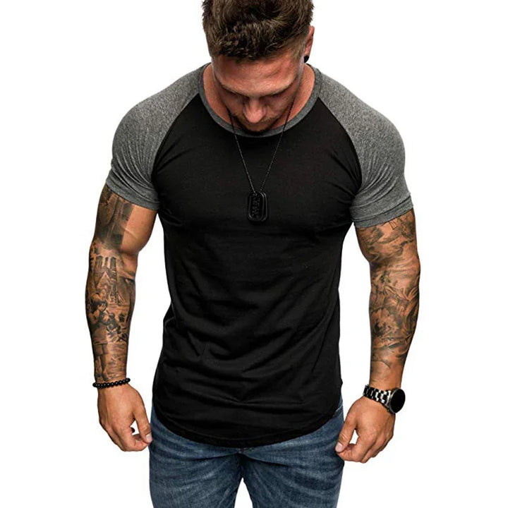 muscular man with tattooed arms wearing black and gray raglan t-shirt and blue jeans