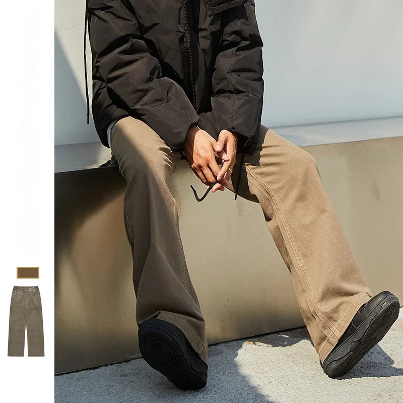 Person wearing brown wide-leg pants and black jacket sitting outdoors on ledge with black shoes