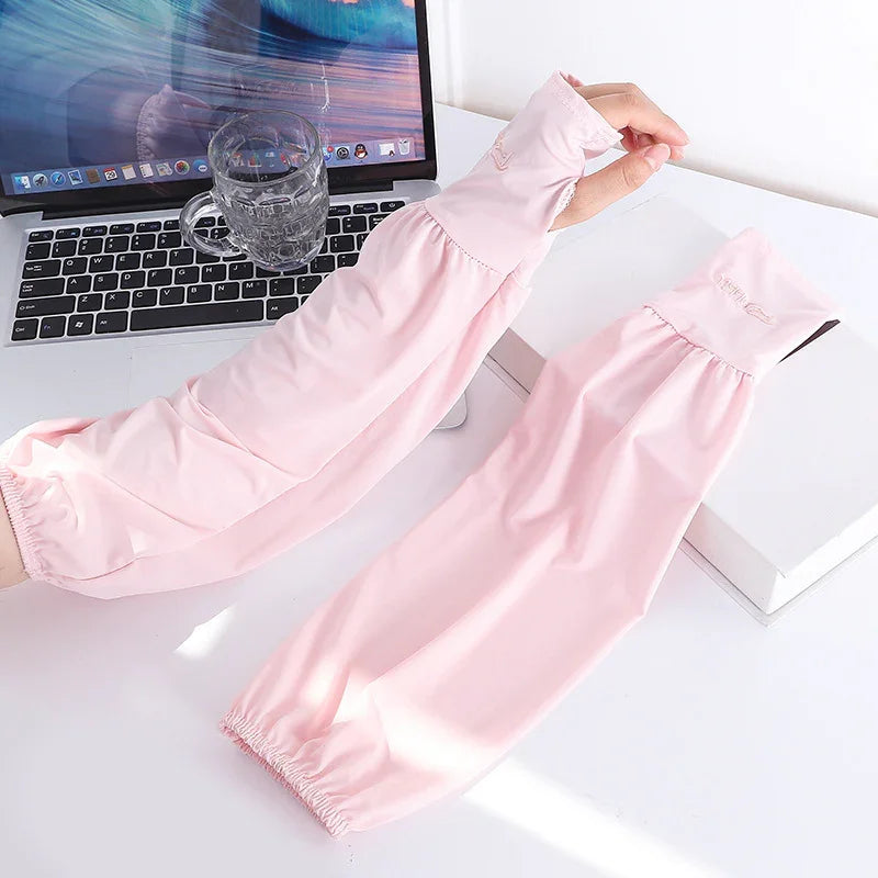 Pair of light pink UV protection arm sleeves on white desk next to laptop and glass cup