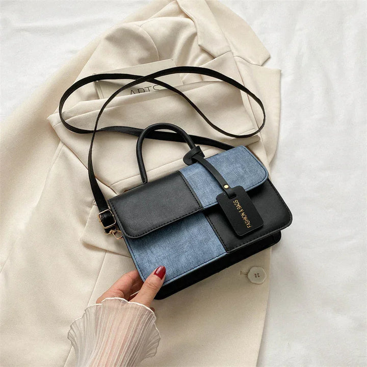 Black and blue colorblock leather handbag with detachable strap on beige blazer background
