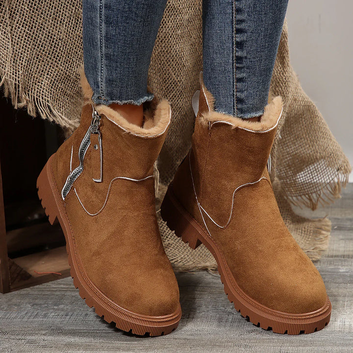 Brown suede ankle boots with fur lining and side zipper worn with blue jeans