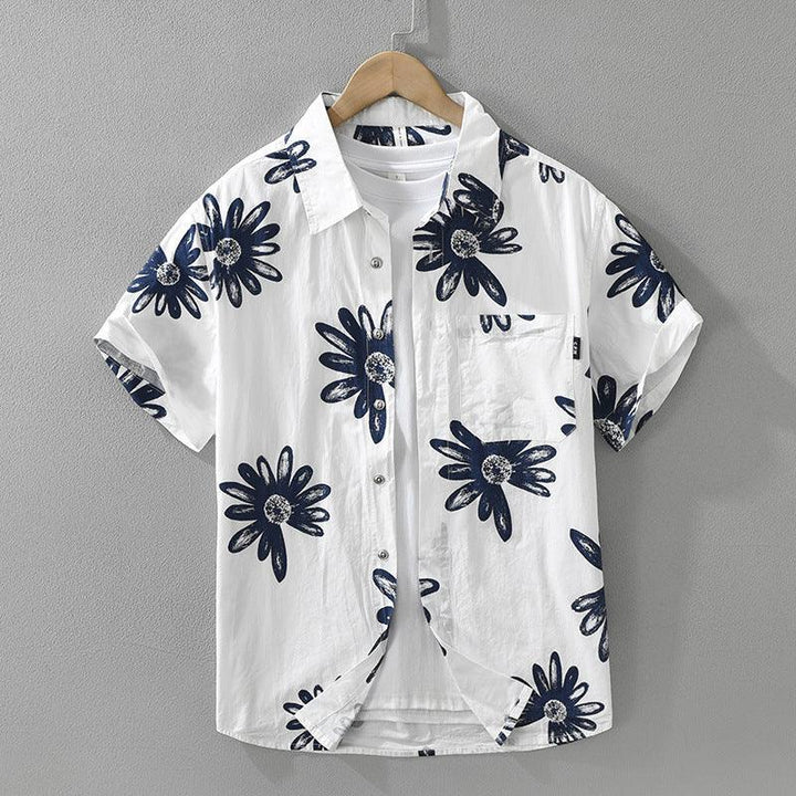 White short-sleeve button-up shirt with large navy blue floral print on wooden hanger