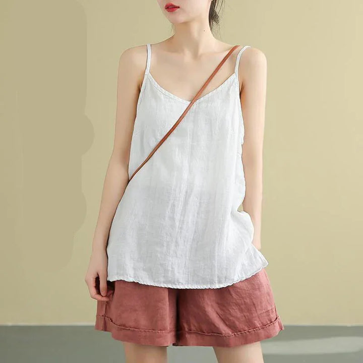 Woman wearing white linen camisole top with thin straps and rust-colored loose shorts against neutral background