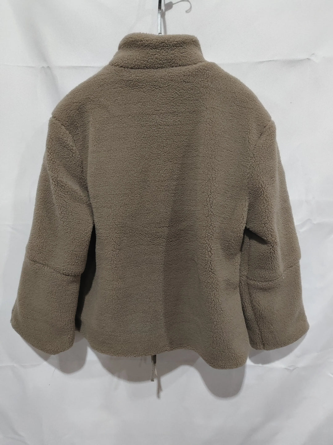 Back view of brown fleece jacket hanging on hanger against white background