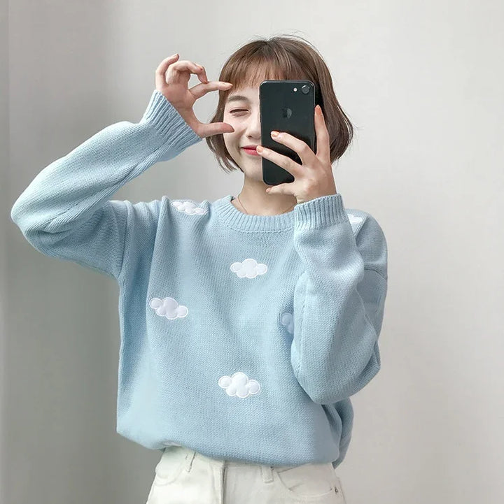 Young woman taking selfie wearing light blue sweater with white cloud patterns and white pants