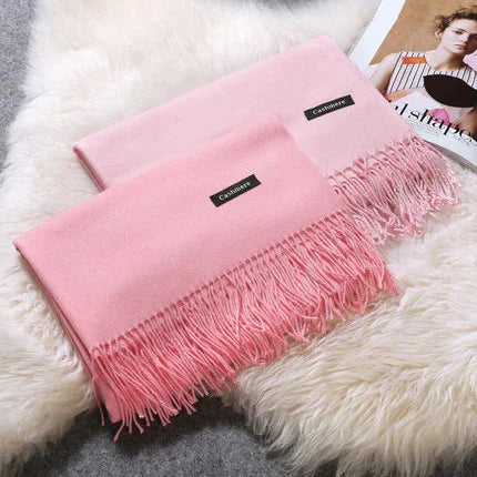 Soft pink cashmere scarves with fringed edges on white fluffy surface next to fashion magazine