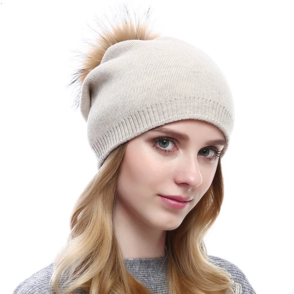 Close-up of woman wearing beige knit winter beanie with fur pom-pom and gray sweater