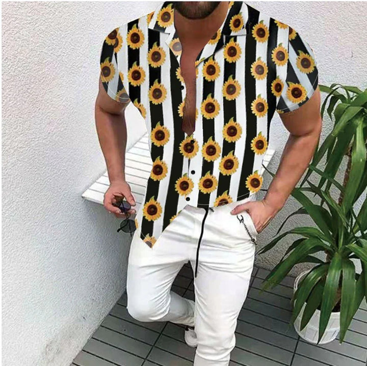 Man wearing black and white striped short-sleeve shirt with sunflower print and white pants, holding sunglasses