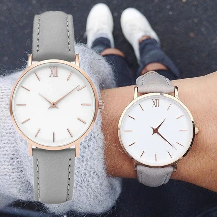 Close-up of two wrists wearing rose gold and gray minimalist analog watches with white faces and Roman numeral XII