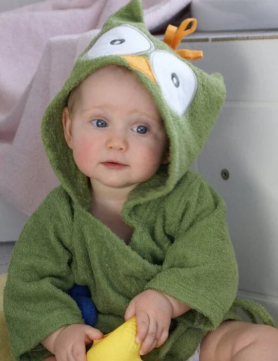 Baby with blue eyes wearing a green hooded towel robe featuring cartoon eyes and holding a yellow toy