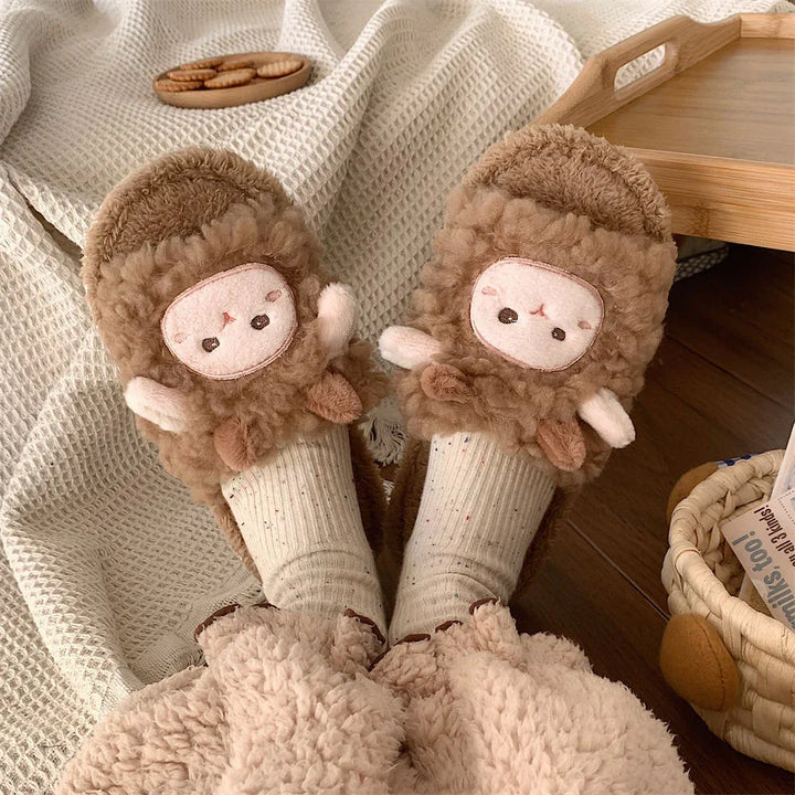 Cozy brown cartoon sheep plush slippers worn with cream knitted socks, soft beige blanket, wooden tray and wicker basket background