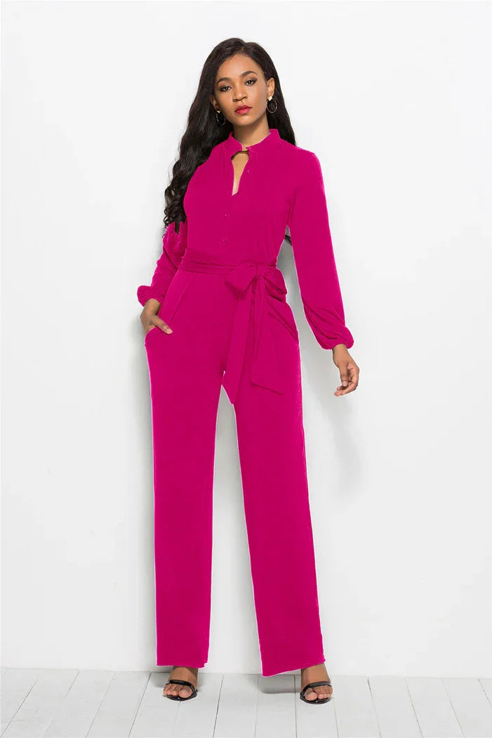 Woman wearing a fuchsia long-sleeve belted jumpsuit with wide-leg pants and black sandals