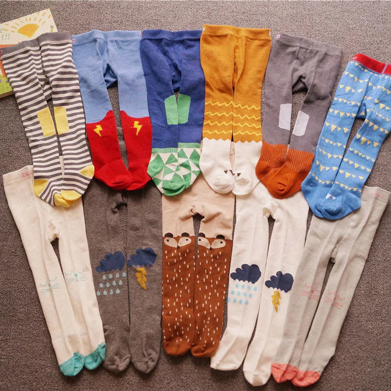 Colorful children's tights with patterns including animals, weather icons, and geometric shapes laid out on a carpet