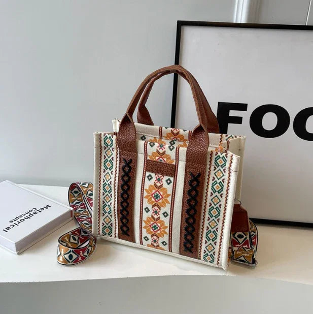 Boho style tote bag with ethnic floral geometric patterns and brown leather handles on white surface
