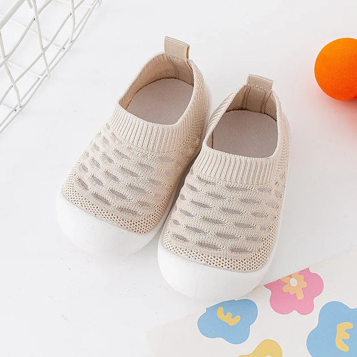 Beige toddler knit shoes with white rubber soles on white background