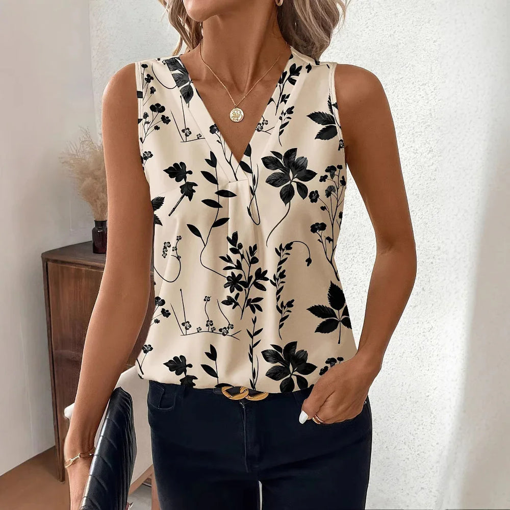 Woman wearing sleeveless beige blouse with black floral print and V-neck, paired with dark pants