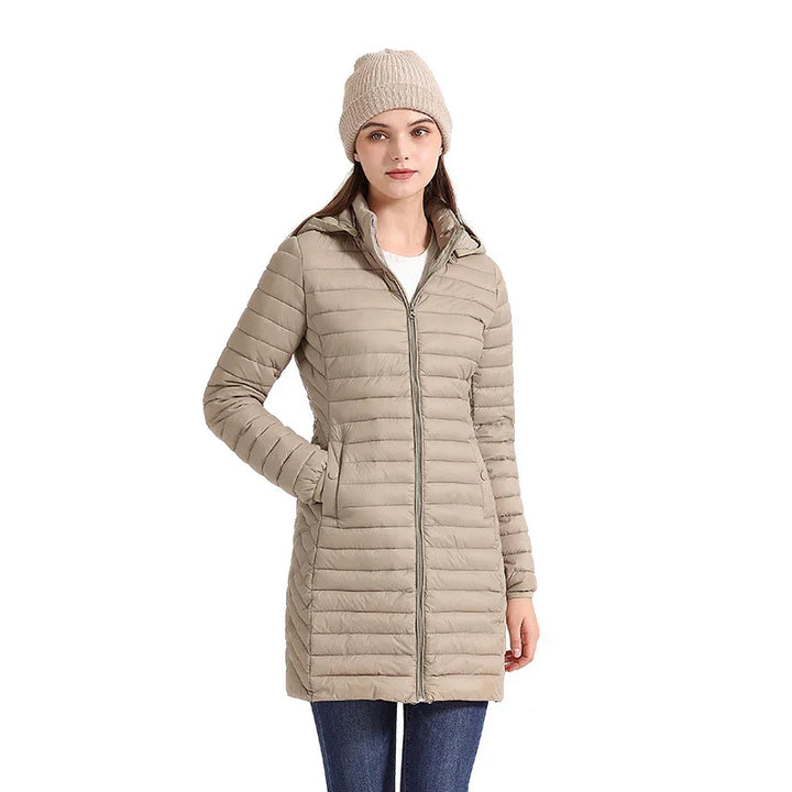 Woman wearing beige long quilted puffer jacket with front zipper and beige knit beanie