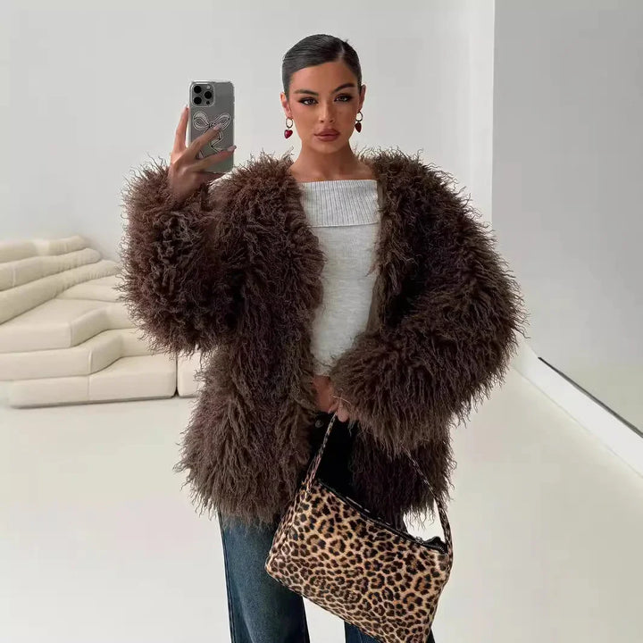 Woman in a brown furry jacket and white top holding a leopard print handbag taking a mirror selfie