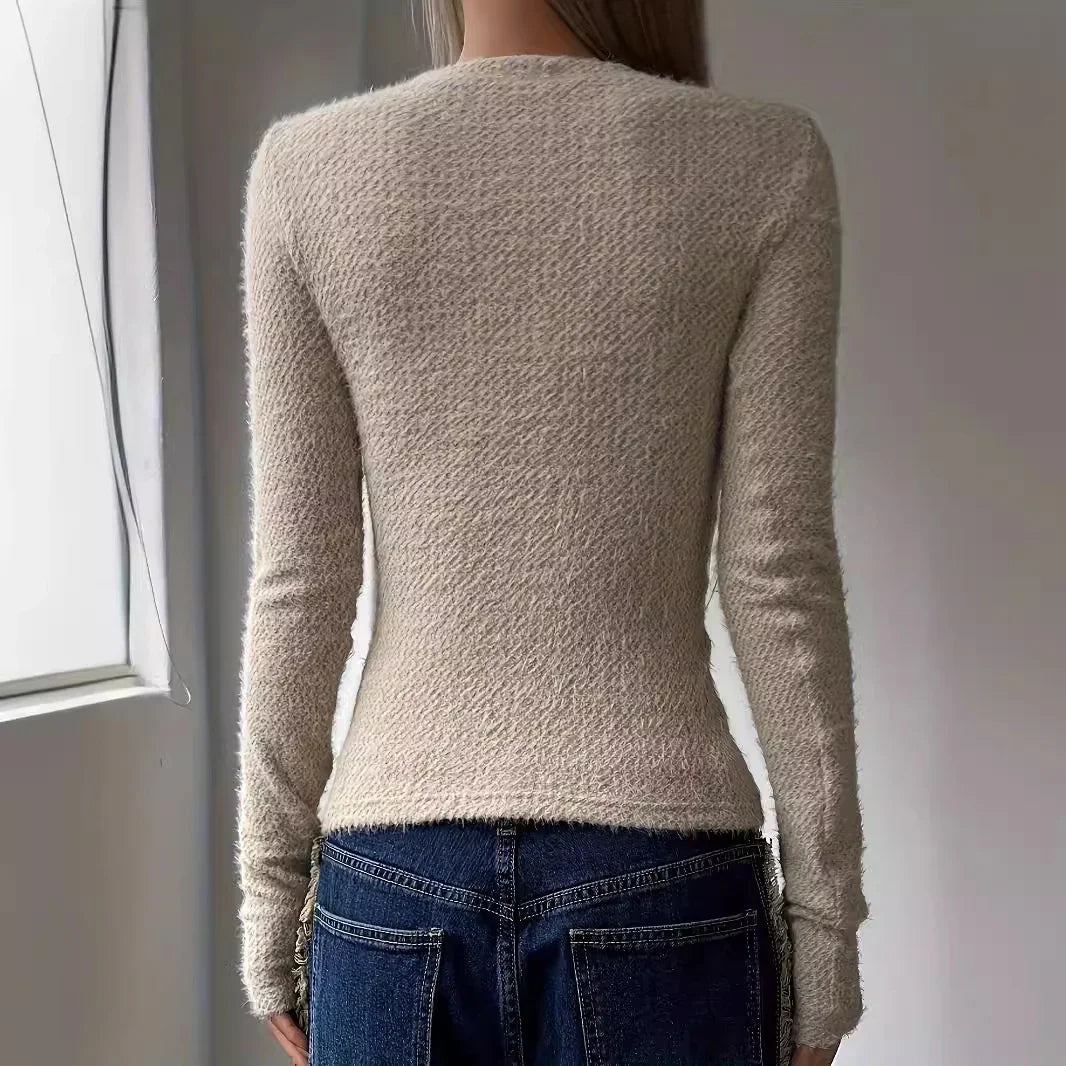 Back view of person wearing beige textured long sleeve sweater and dark blue denim jeans indoors