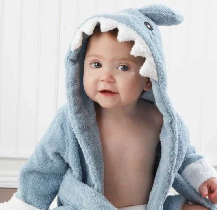 Baby wearing a soft blue shark-themed hooded towel with white teeth design
