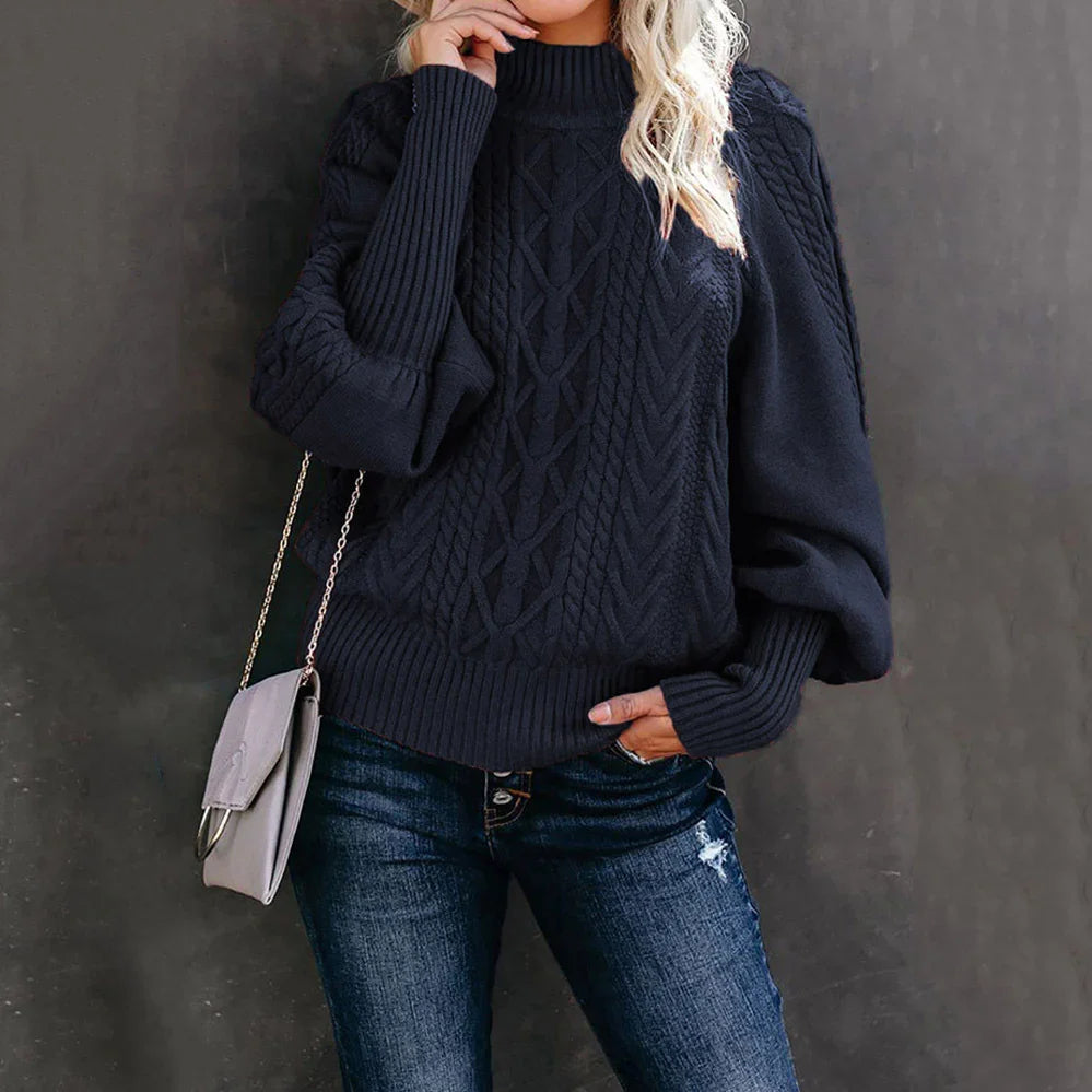 Woman wearing black cable knit sweater with balloon sleeves, blue distressed jeans, and gray crossbody bag