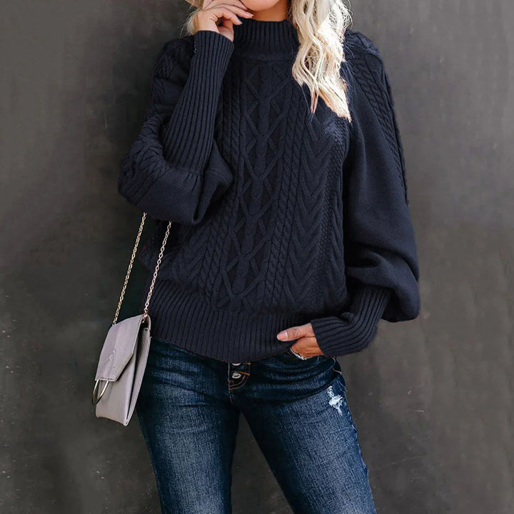 Woman wearing black cable knit sweater with balloon sleeves, blue distressed jeans, and gray crossbody bag