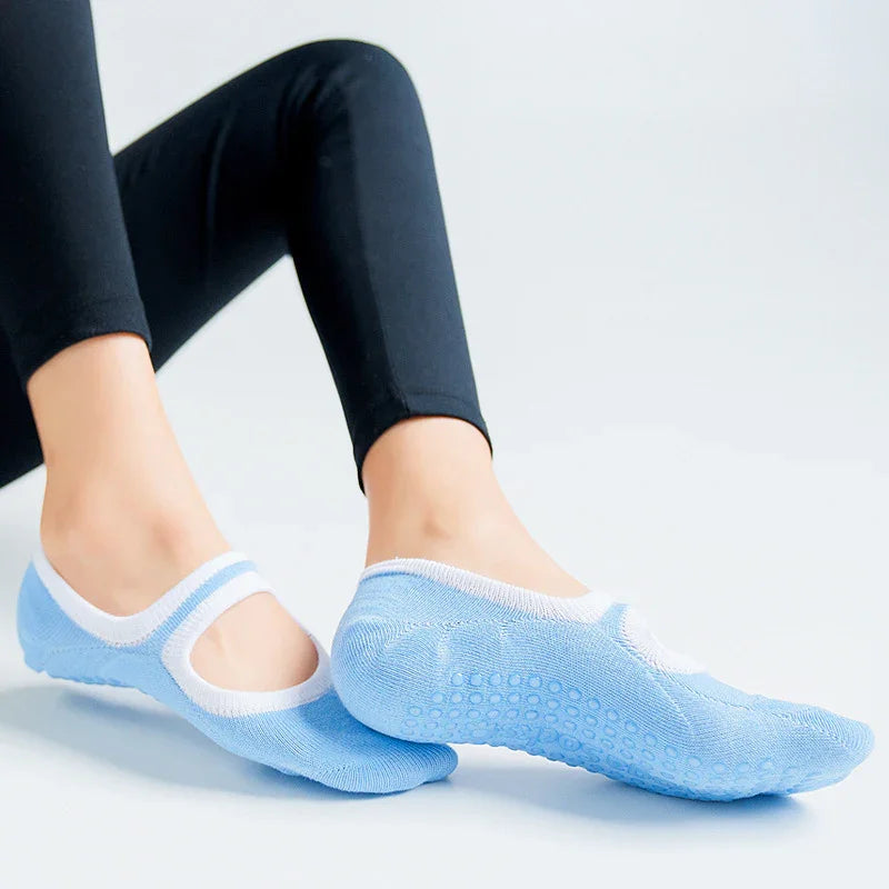 Close-up of feet wearing light blue non-slip yoga grip socks with white trim and black leggings