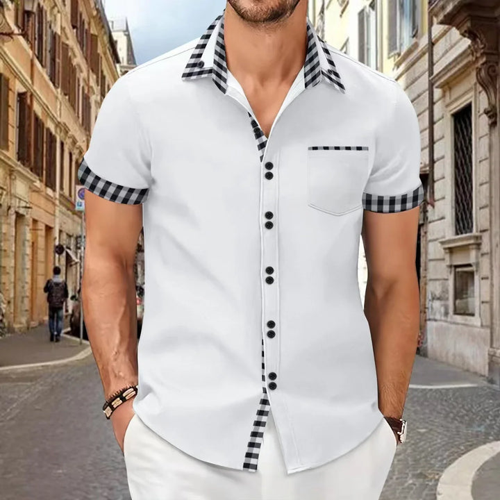 Man wearing white short-sleeve shirt with black and white checkered collar and sleeve cuffs in urban street setting