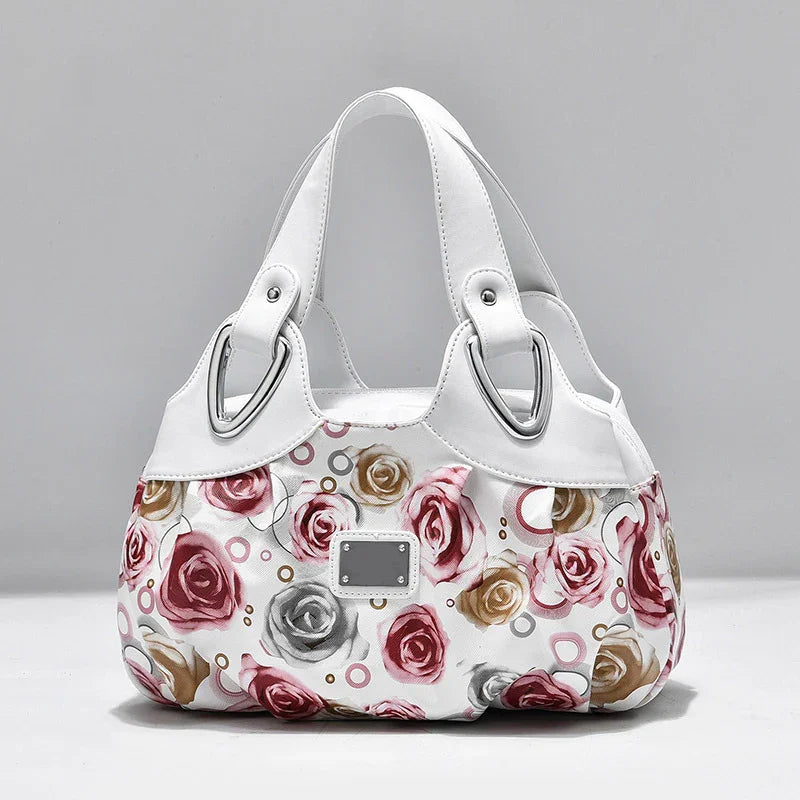 White floral handbag with pink, gold, and gray rose patterns and silver buckle accents