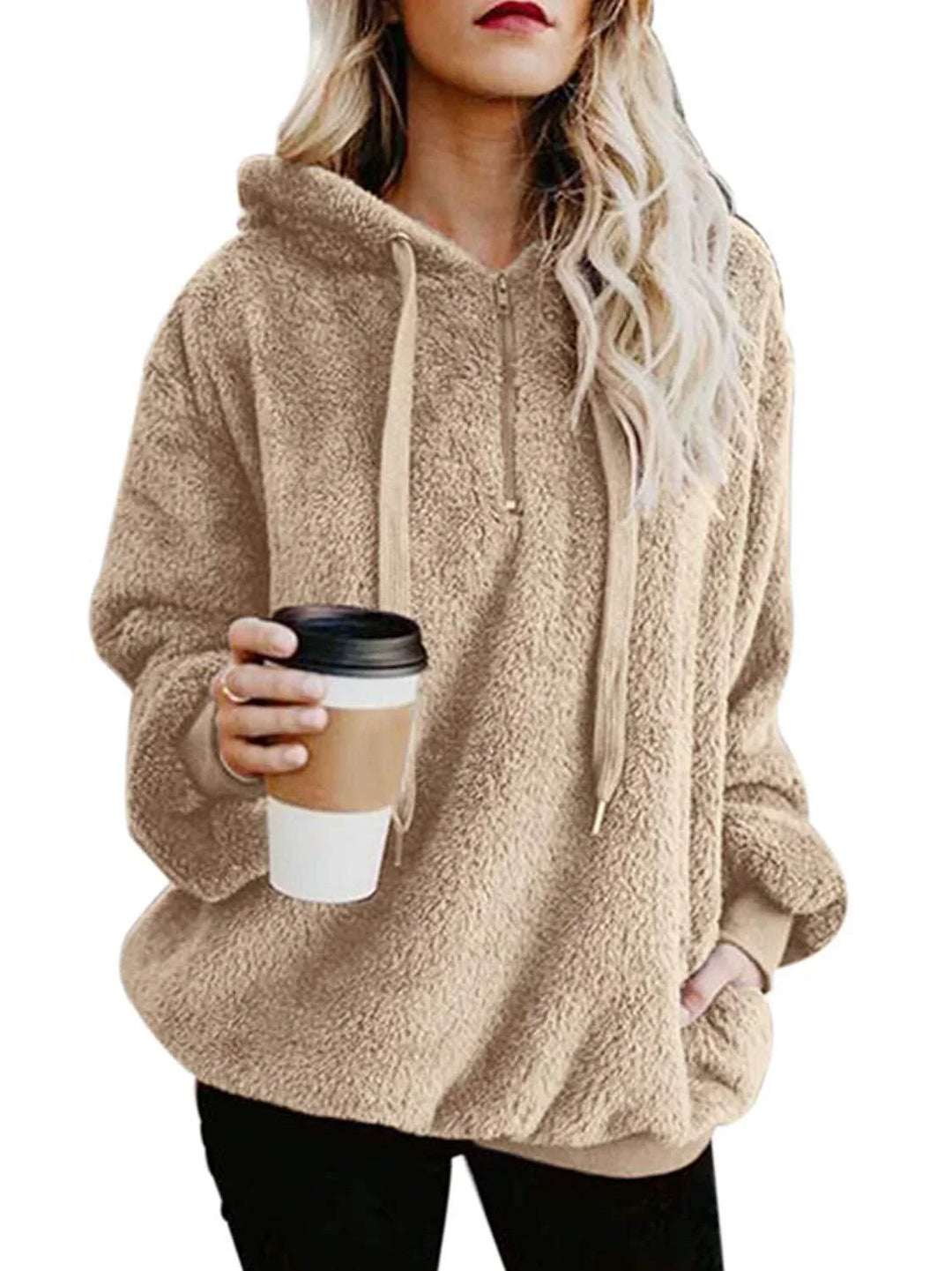 Woman wearing beige sherpa fleece hoodie holding takeaway coffee cup