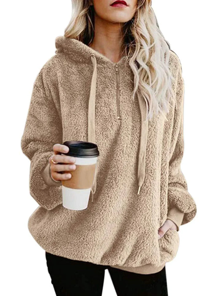 Woman wearing beige sherpa fleece hoodie holding takeaway coffee cup